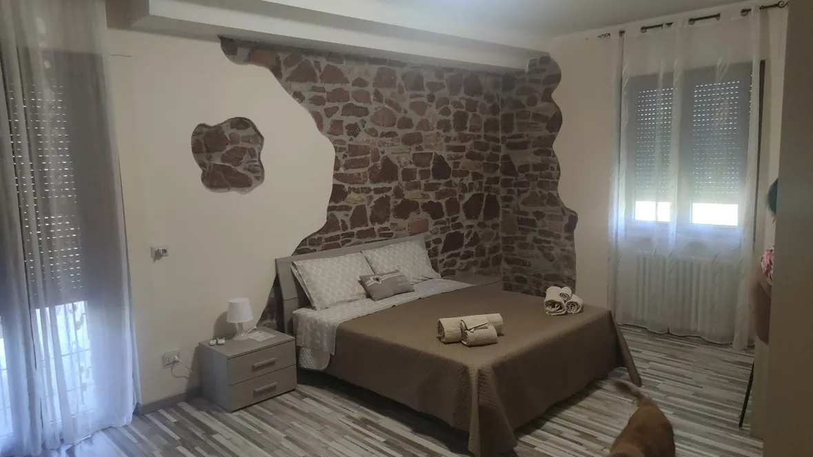 Camera con letto matrimoniale e parete in pietra