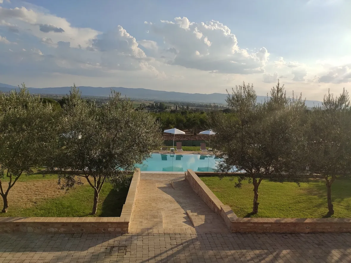La piscina con gli ulivi e le nuvole sopra la valle